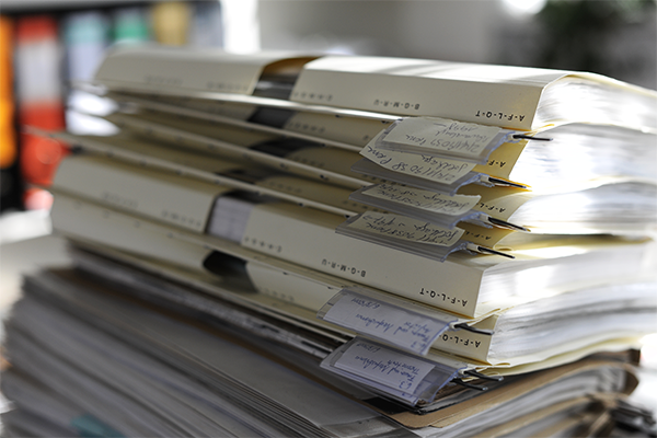 Das in Aktendeckeln abgeheftete Material ist sorgfältig und sichtbar verschlagwortet. Die Aktendeckel sind aufeinandergestapelt.